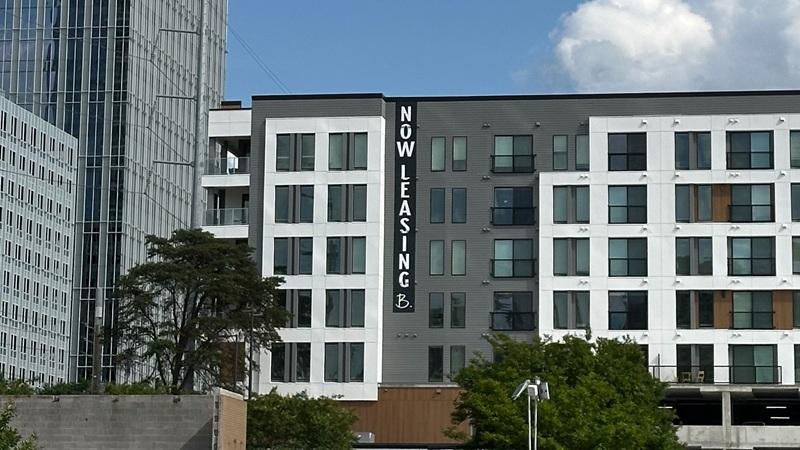 "Now Leasing" sign on mixed-use multifamily building in Sun Belt