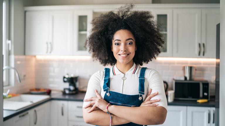 Smiling woman with folded arms in kitchen