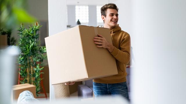 Student carries box as he moves into apartment